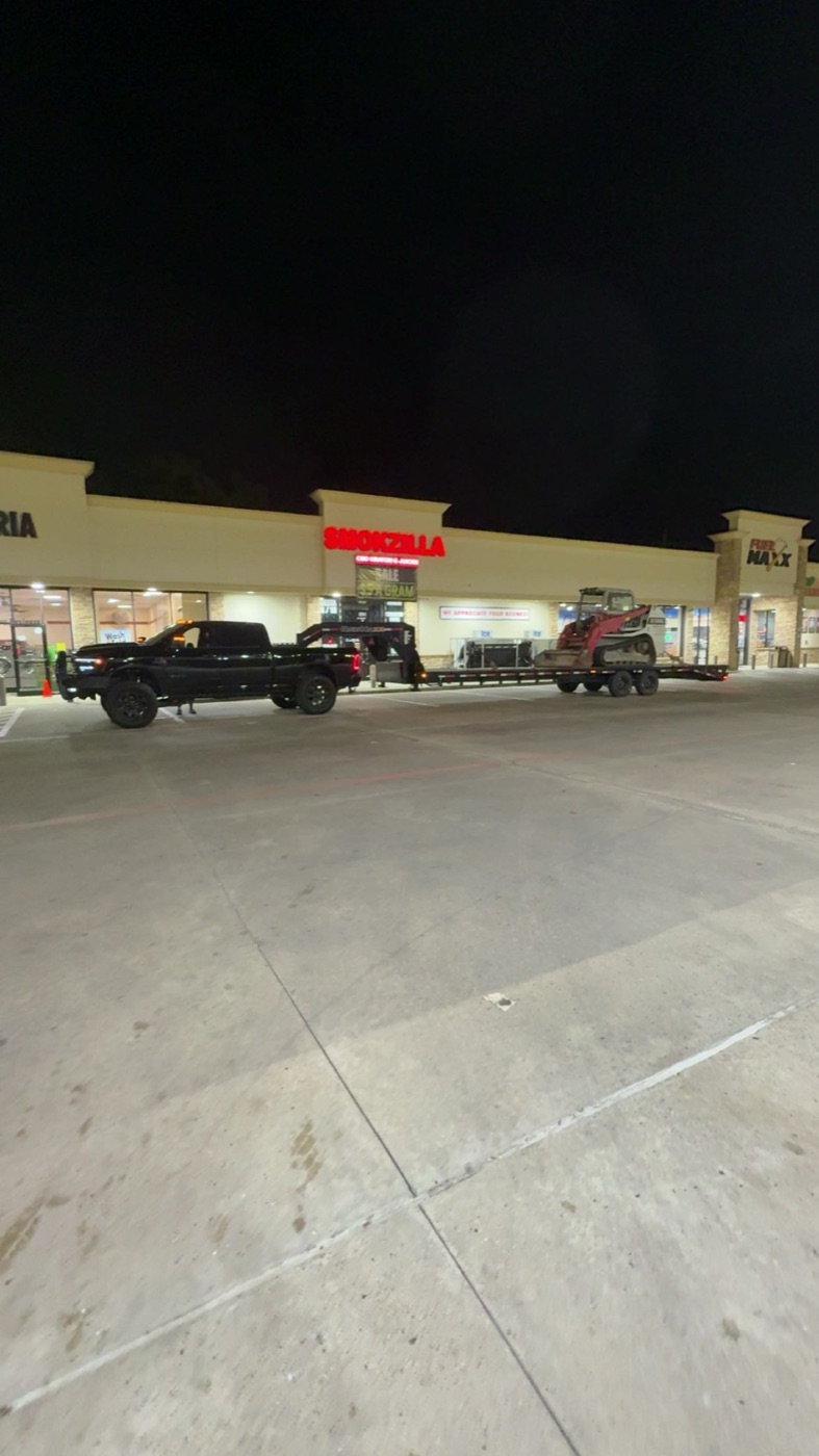 LeadFoot Express hauling a skid steer at night — dispatch runs 24/7